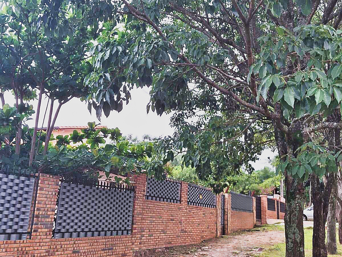 Paraguay Immobilie: Eine eindrucksvolle Ziegelmauer mit Metallzäunen und Bäumen schützt ein Grundstück in Paraguay.