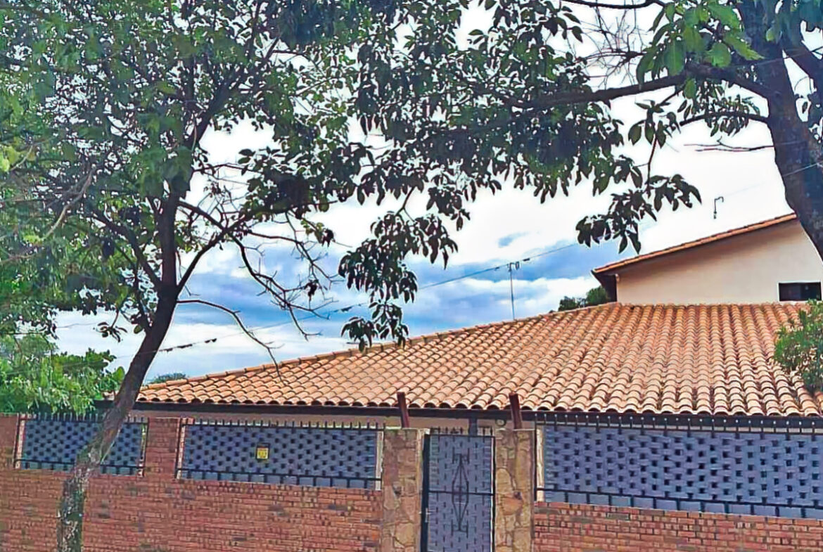 Immobilie Paraguay: Gemütliches Haus mit Terrakotta-Dach, Backsteinmauer und grüner Bepflanzung für entspanntes Wohnen.