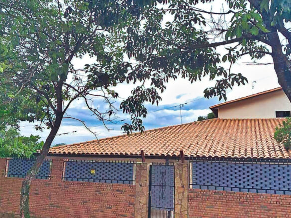 Immobilie Paraguay: Gemütliches Haus mit Terrakotta-Dach, Backsteinmauer und grüner Bepflanzung für entspanntes Wohnen.