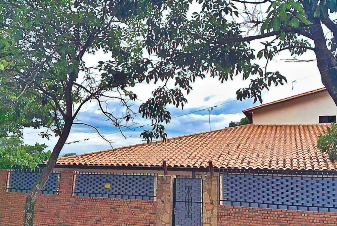 Immobilie Paraguay: Gemütliches Haus mit Terrakotta-Dach, Backsteinmauer und grüner Bepflanzung für entspanntes Wohnen.