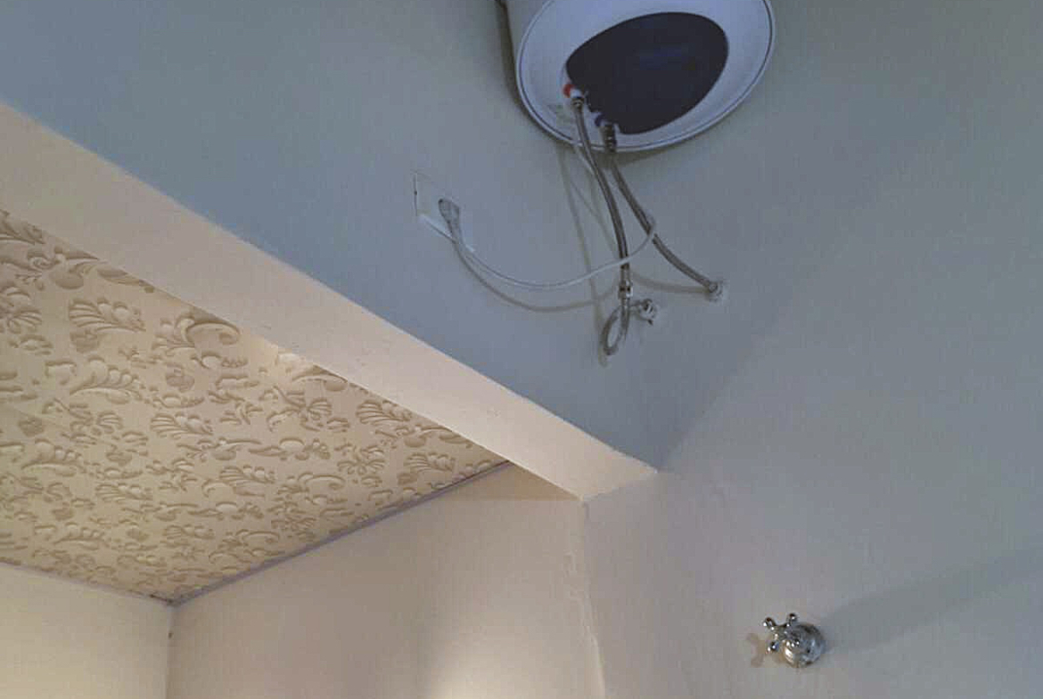 Warmwasserbereiter und dekorative Stuckdecke in einem Badezimmer einer Paraguay-Immobilie.