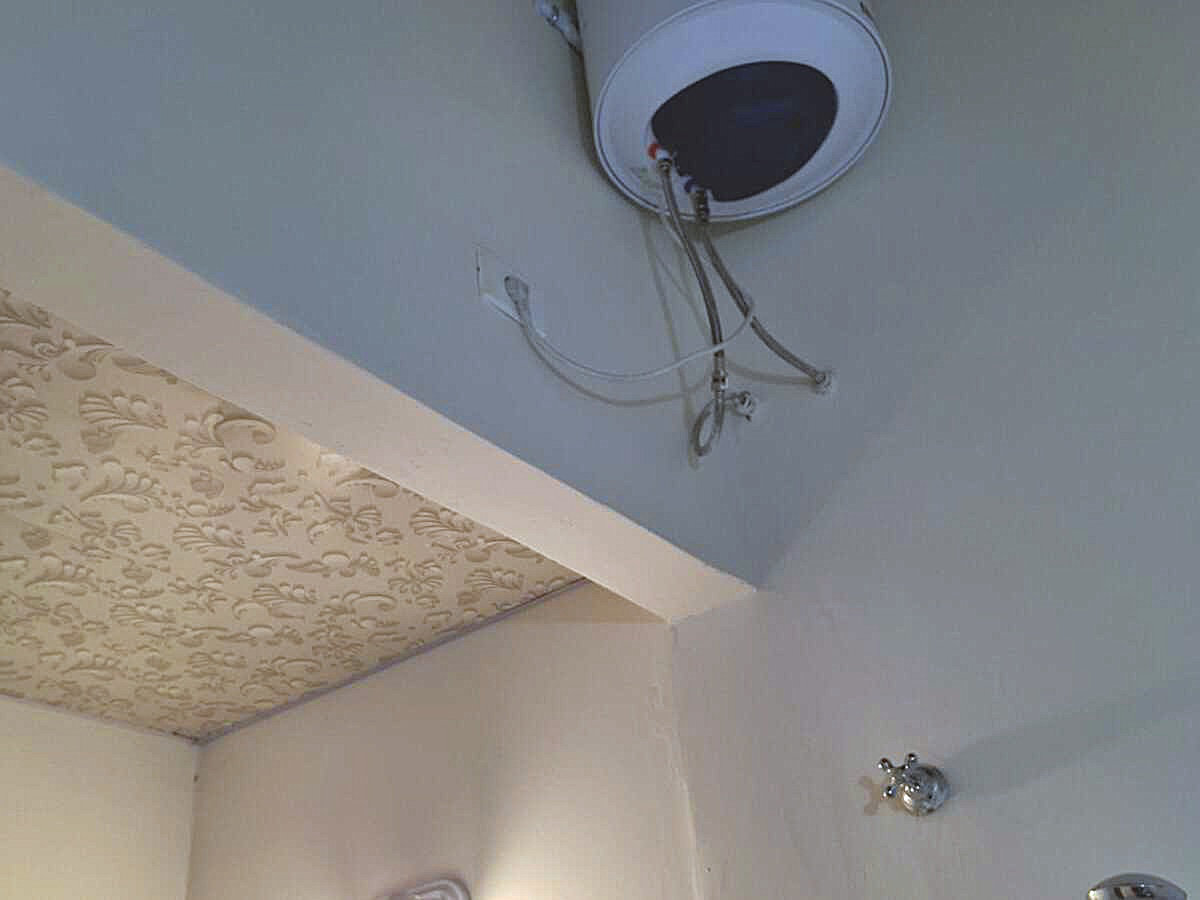 Warmwasserbereiter und dekorative Stuckdecke in einem Badezimmer einer Paraguay-Immobilie.