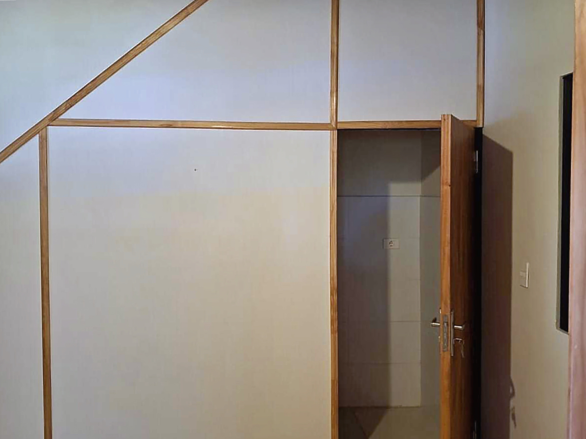 Detailansicht einer Immobilie in Paraguay mit weißer Wandverkleidung, Holzleisten und offener Holztür zu einem Nebenraum.