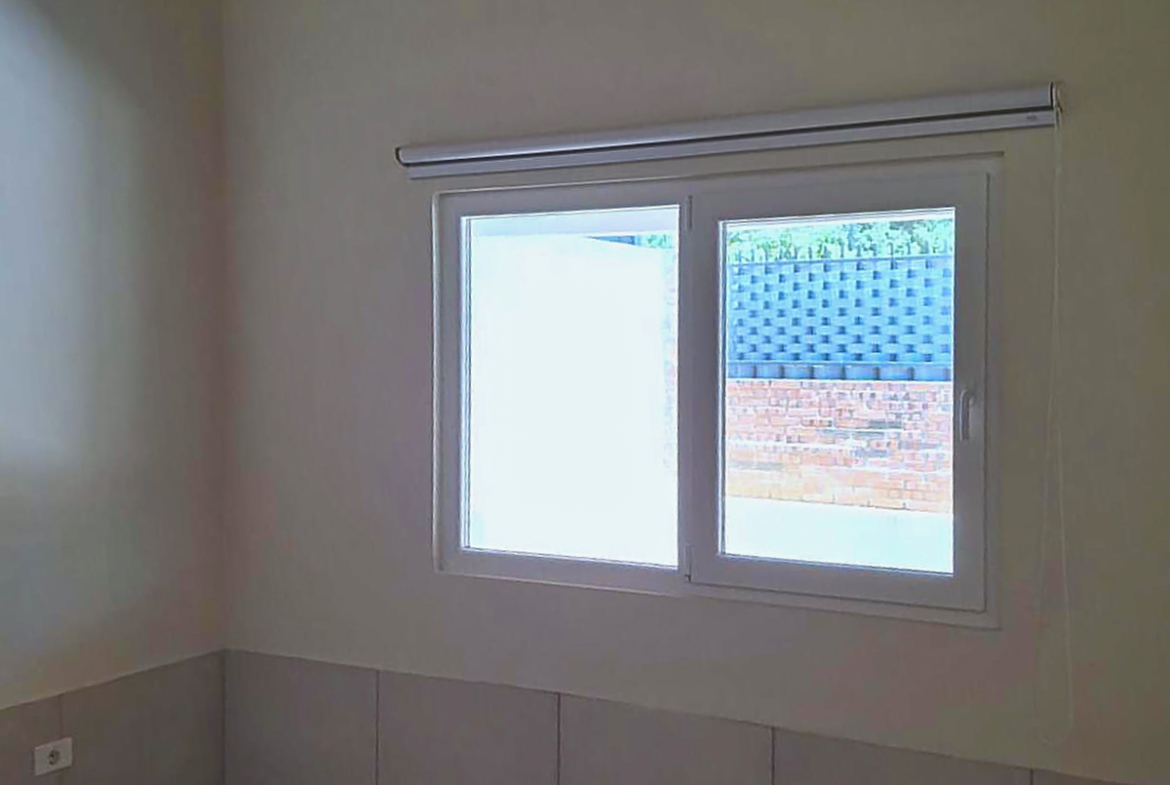 Innenansicht eines hellen Zimmers mit modernem Fenster und Rollokasten, Immobilie in Paraguay.