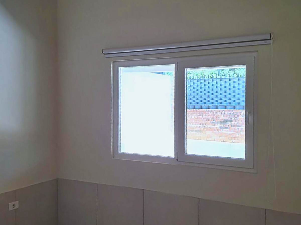 Innenansicht eines hellen Zimmers mit modernem Fenster und Rollokasten, Immobilie in Paraguay.