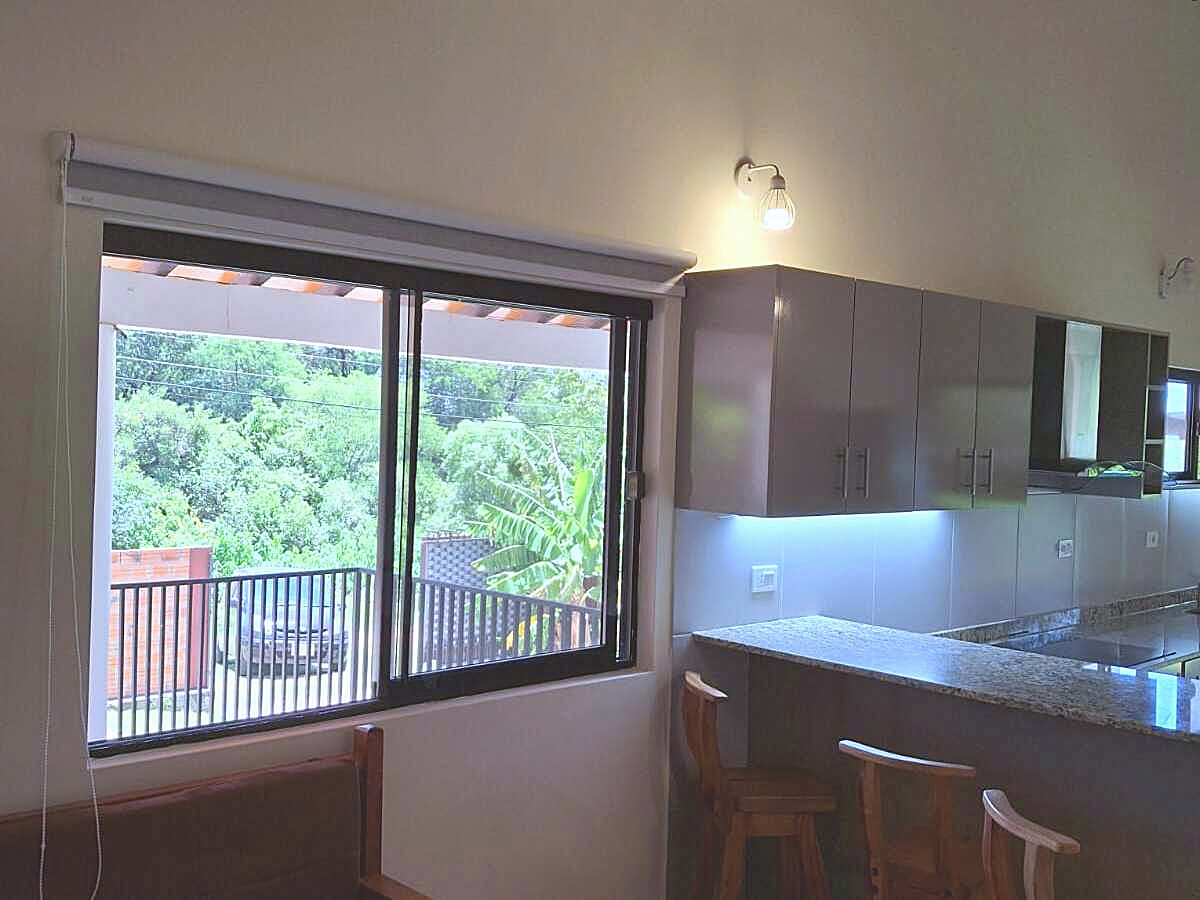 Moderne Küche in Paraguay mit stilvollen grauen Schränken, Granitarbeitsplatte und einem Fensterblick ins Grüne.