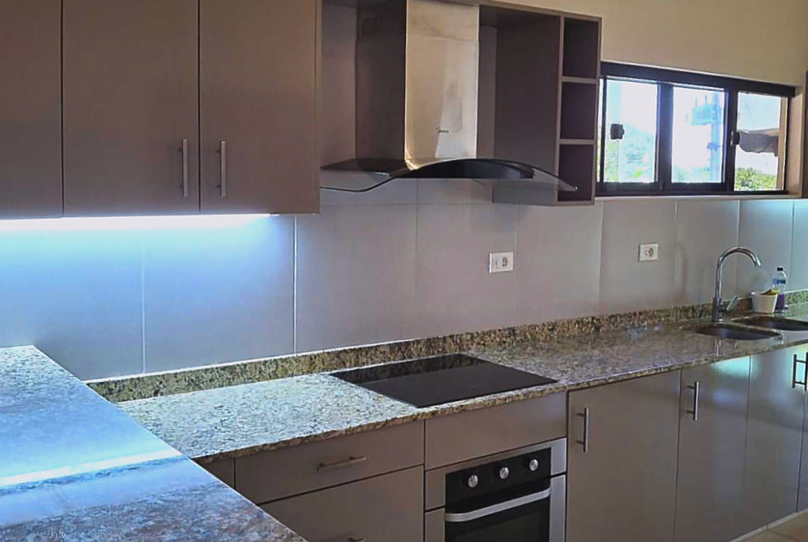 Moderne Einbauküche mit Granitarbeitsplatte, Edelstahlgeräten und viel Stauraum in Paraguay.