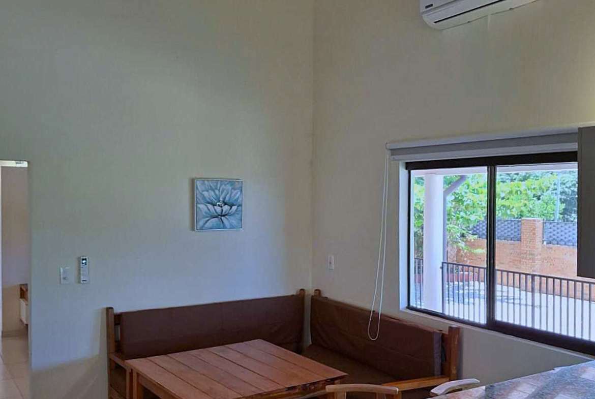 Heller Essbereich in Paraguay mit Holzmöbeln, Klimaanlage und Fenster zum Garten.