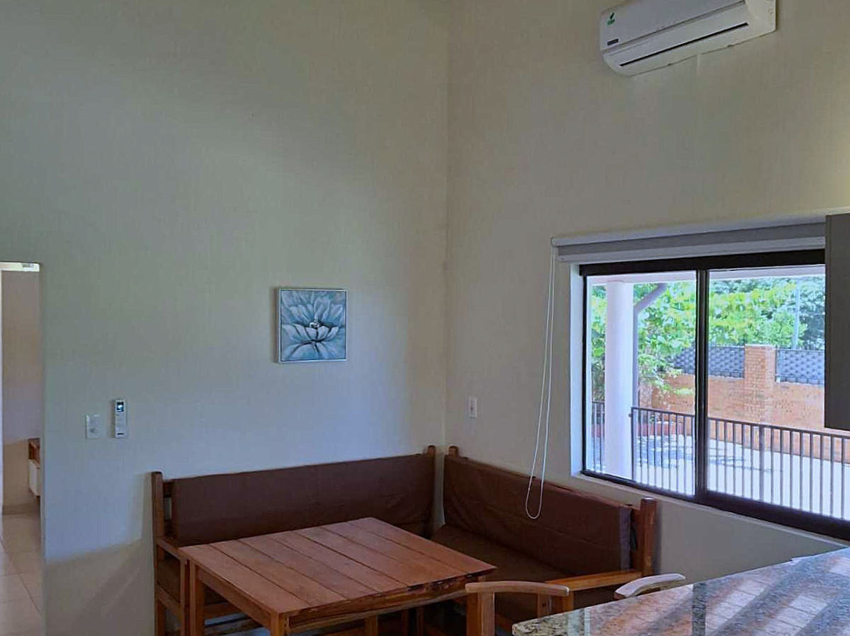 Heller Essbereich in Paraguay mit Holzmöbeln, Klimaanlage und Fenster zum Garten.