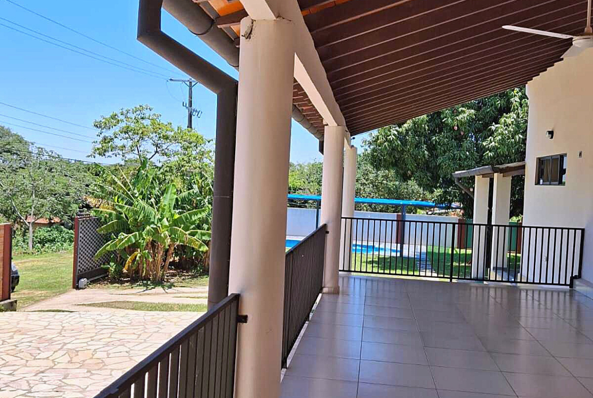 Geräumige überdachte Terrasse eines Hauses in Paraguay mit Blick auf den Garten und Pool.