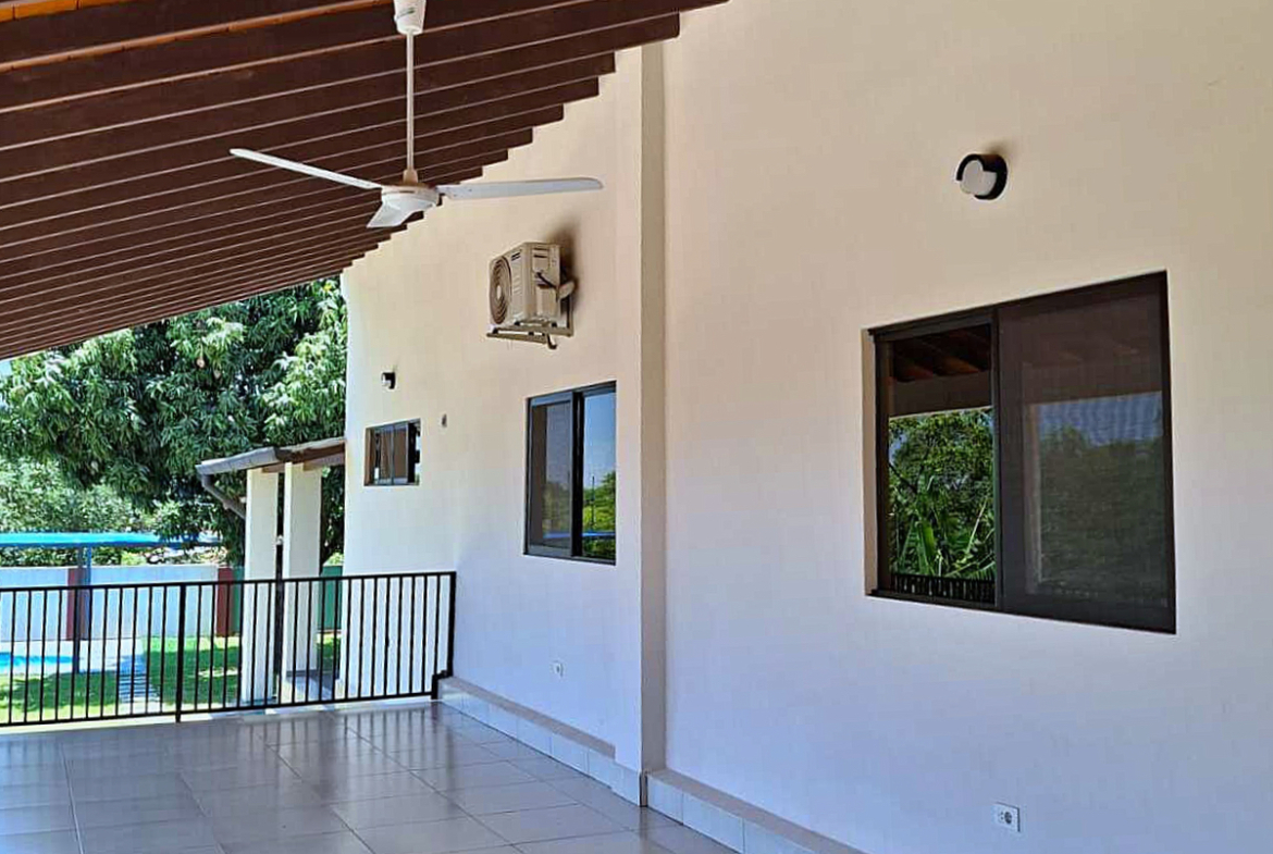 Überdachte Terrasse mit Deckenventilator, Klimaanlage und Grünblick am Haus in Paraguay.