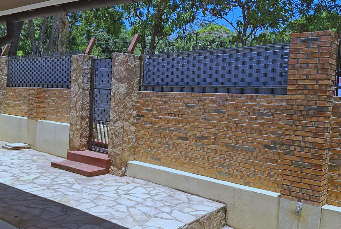 Robuste Ziegel- und Steinmauer mit elegantem Metallzaun und Tor für Sicherheit und Privatsphäre in Paraguay.