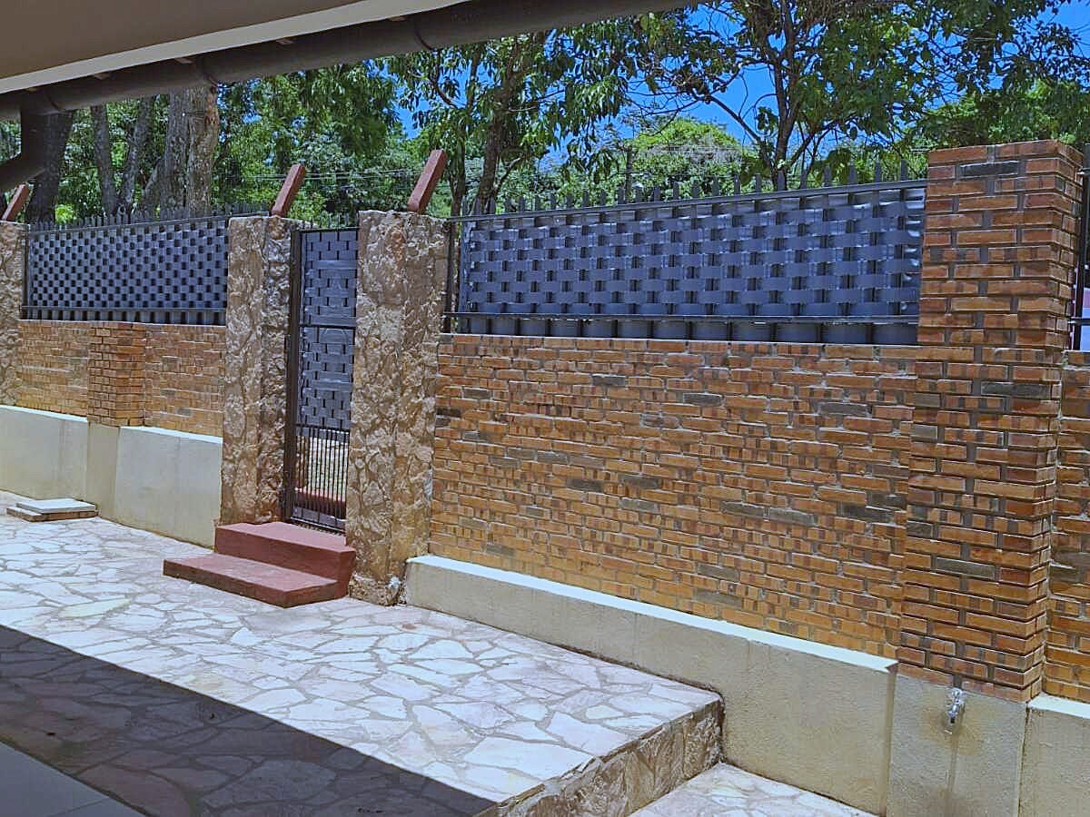 Robuste Ziegel- und Steinmauer mit elegantem Metallzaun und Tor für Sicherheit und Privatsphäre in Paraguay.