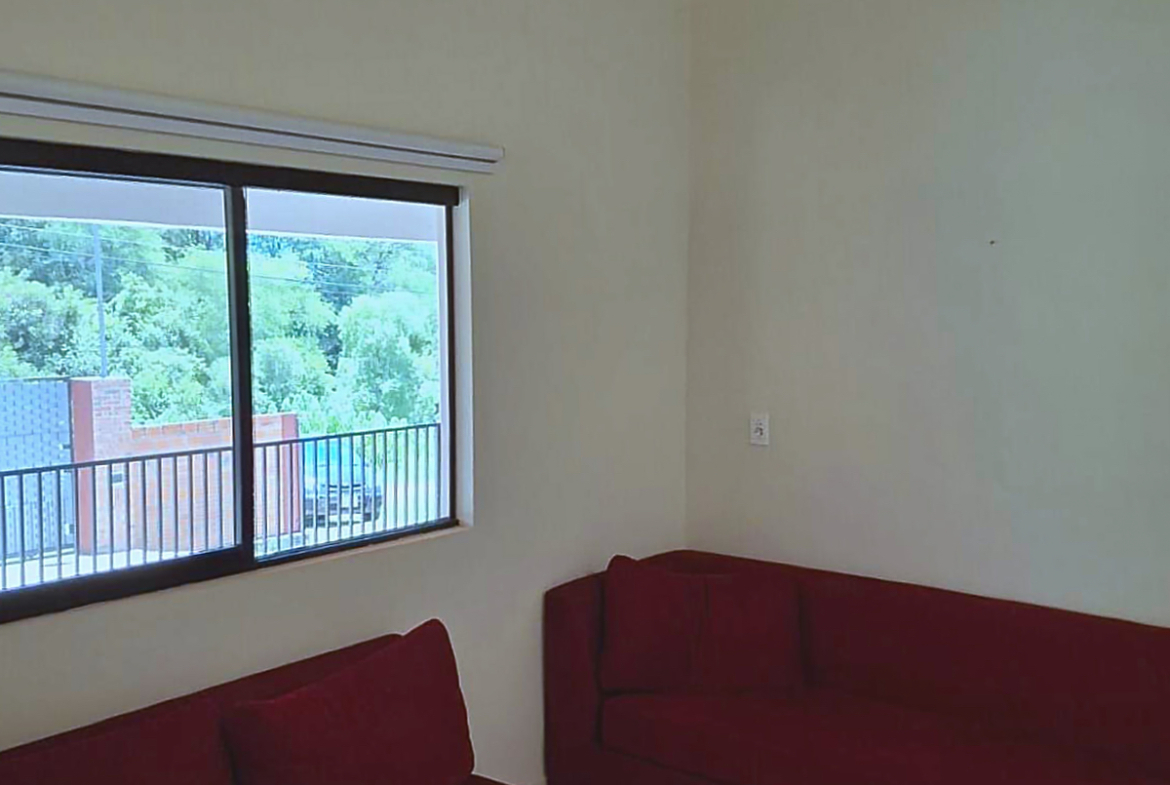 Helles Wohnzimmer in Paraguay mit gemütlichem roten Sofa und weitem Blick ins Grüne.