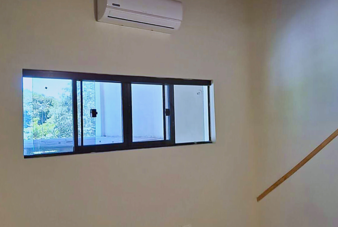 Heller Wohnraum in Paraguay mit Klimaanlage, Fensterblick ins Grüne und moderner Ausstattung.
