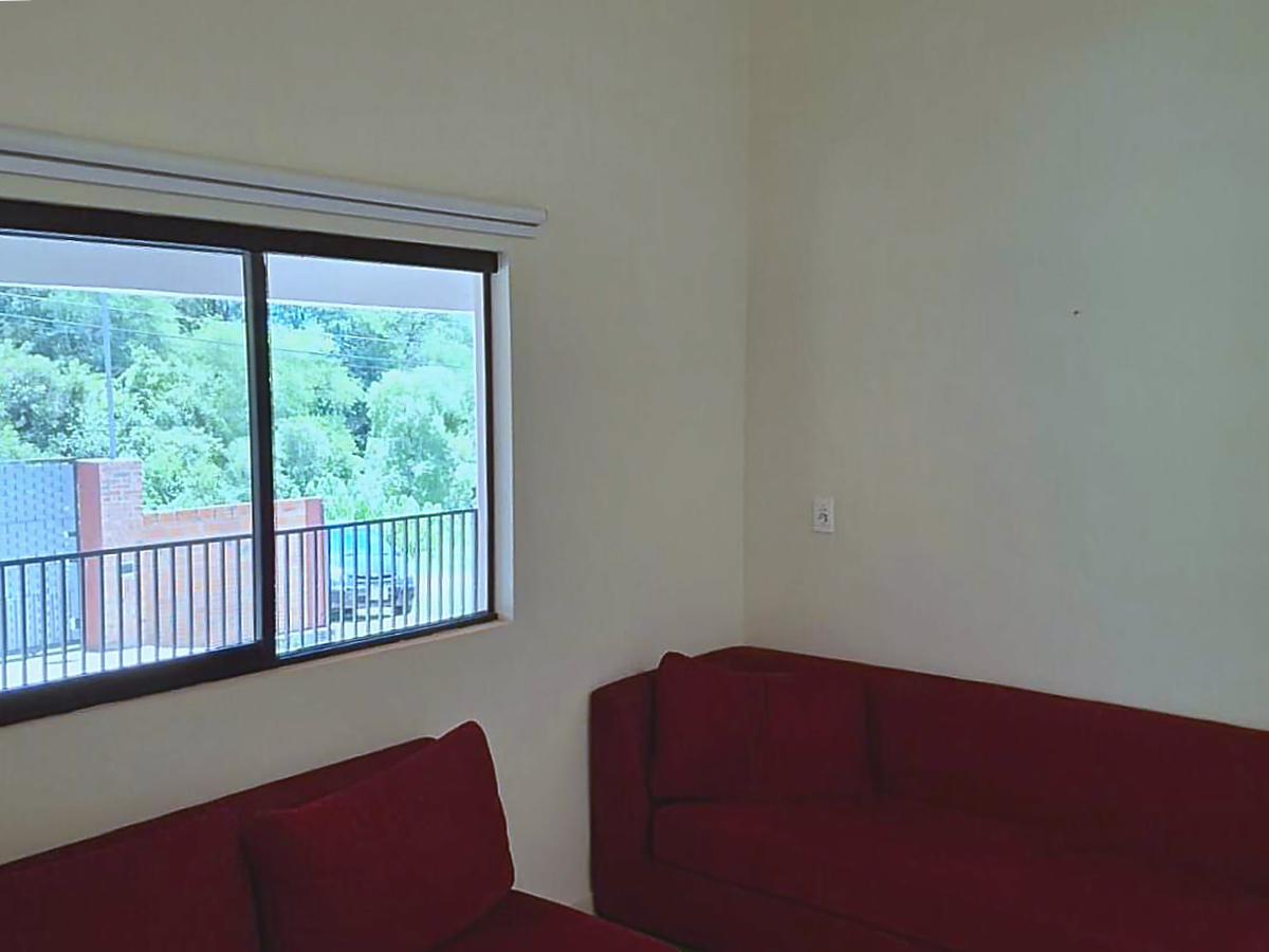 Helles Wohnzimmer in Paraguay mit gemütlichem roten Sofa und weitem Blick ins Grüne.